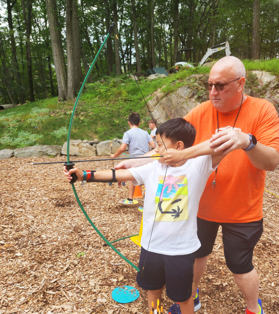 child getting archery lesson